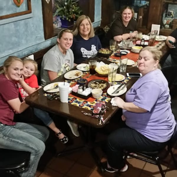 Group of women and a child smiling around a table with Mexican food and drinks at Pueblo Viejo.