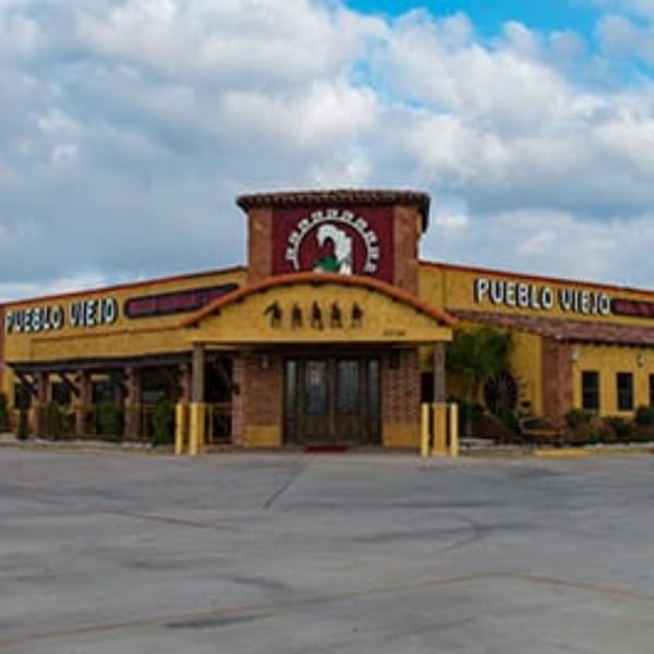 Exterior of Pueblo Viejo Mexican Restaurant, a yellow building with a red tile roof and prominent signage.