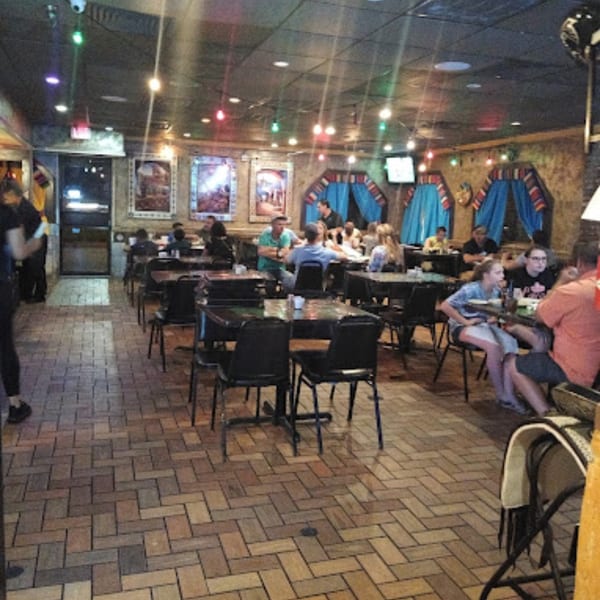 Diners seated at tables in Pueblo Viejo Mexican Restaurant, featuring colorful decor and brick-patterned flooring.