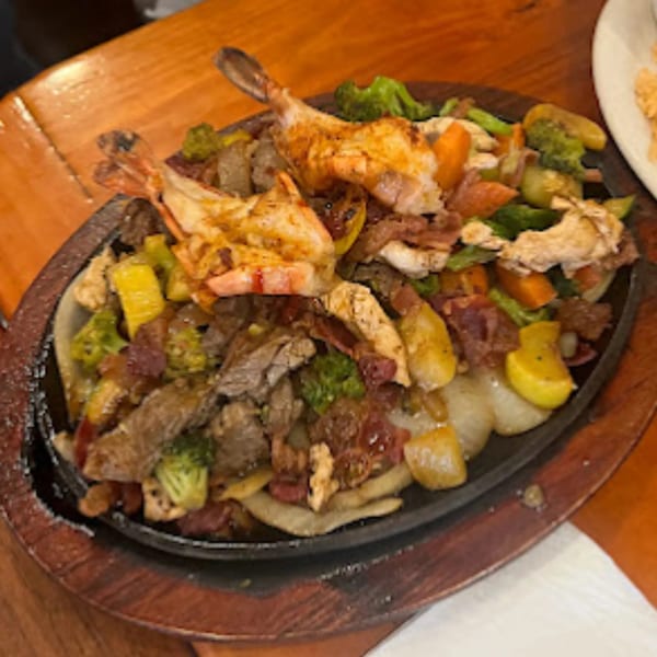 Sizzling fajitas with shrimp, steak, chicken, and vegetables on a hot plate at Pueblo Viejo.