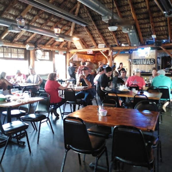 Diners enjoying meals at wooden tables under a thatched roof at Pueblo Viejo Mexican Restaurant.