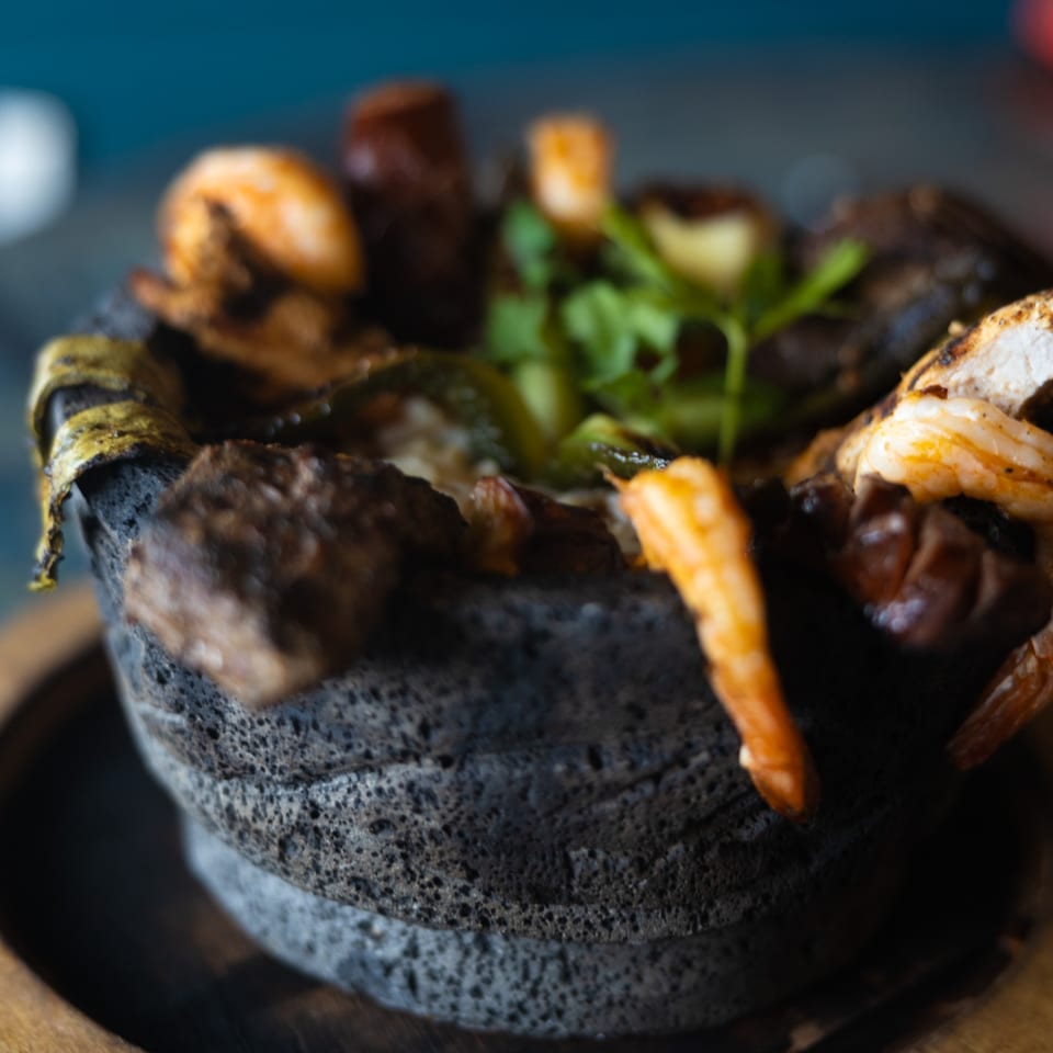 Pueblo Viejo's molcajete dish, filled with grilled meats, shrimp, and vegetables, served in a traditional stone bowl.