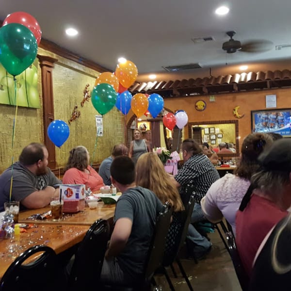 A group of people celebrating with colorful balloons at Pueblo Viejo Mexican Restaurant.
